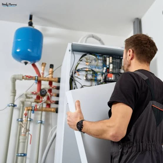 Technician accessing an indoor heating system beside household piping
